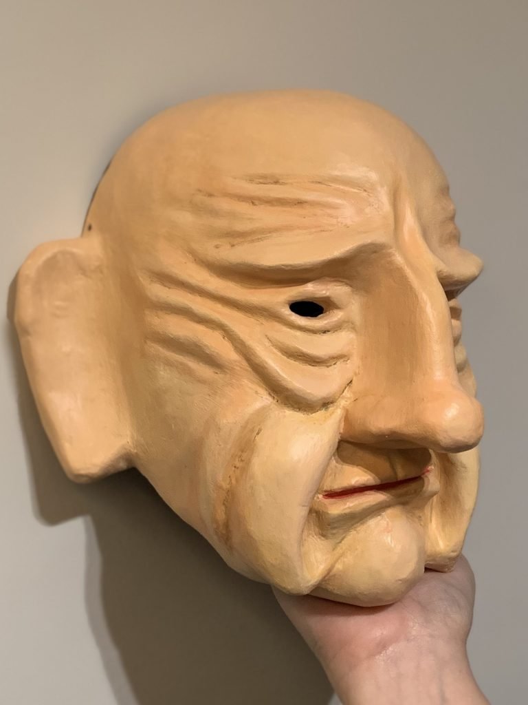 Máscara teatral Velho, feita com materiais reciclados como rolos de papel-toalha e filtros de café.